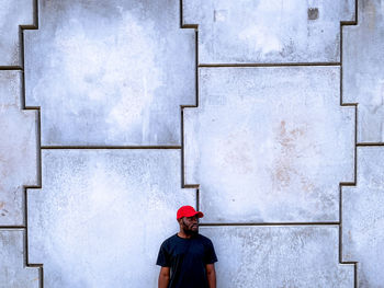 Low section of man with a red cap standing against wall