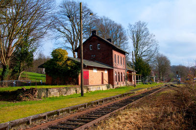 Railroad tracks by old building against sky