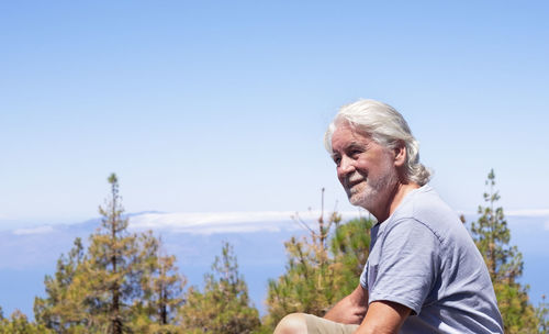 Man with arms raised against clear blue sky