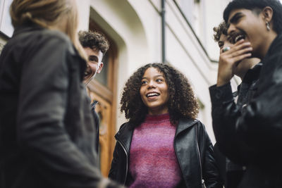 Happy girl talking with male and female teenage friends at street