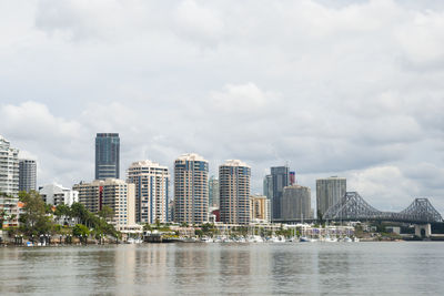 Buildings by river against sky in city