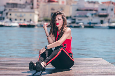 Portrait of woman sitting on pier at sea