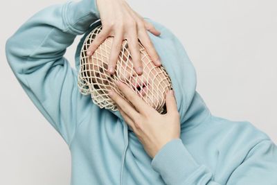 Man wearing mesh bag covering face with hands