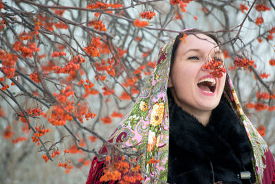 Close-up of young woman with autumn tree against sky