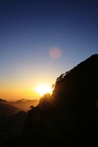 Scenic view of silhouette mountains against clear sky during sunset