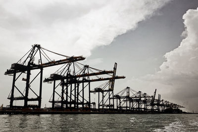 Cranes at pier against sky
