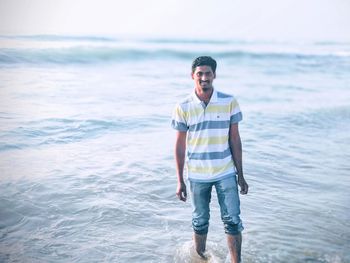 Portrait of smiling young man standing at beach