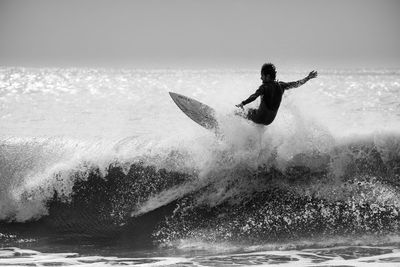 Man surfing in sea against sky