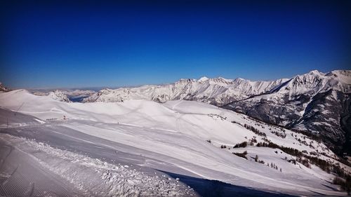 Scenic view of snowcapped mountains against clear blue sky