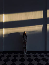 Rear view of woman standing against wall