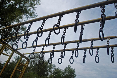 Low angle view of metal hanging against sky