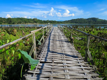 Walkway leading towards bridge against sky