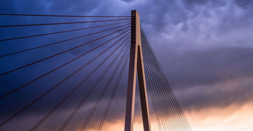 Low angle view of suspension bridge against cloudy sky