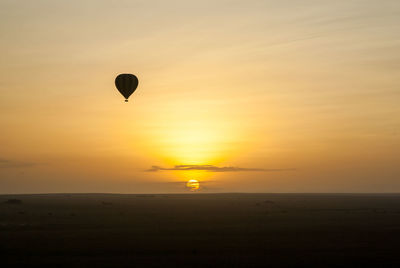 Hot air balloon flying against sky during sunset