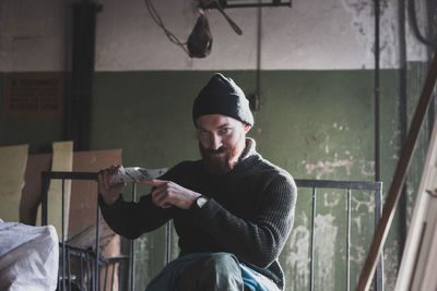 Portrait of young man holding broken glass at abandoned house