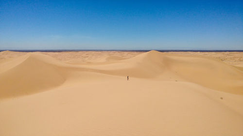 Sand dunes in desert against clear blue sky