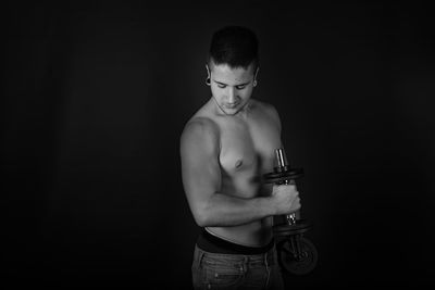 Full length of shirtless man standing against black background