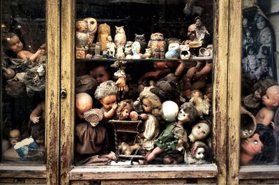 Old dolls and toys by window at abandoned store