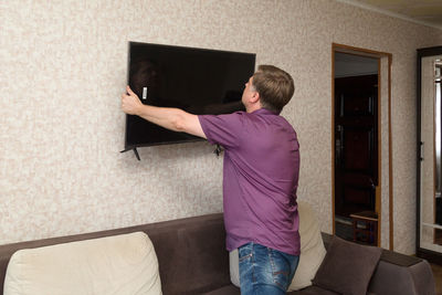 Full length of man standing on sofa at home