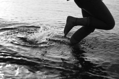 Low section of person walking in sea at beach