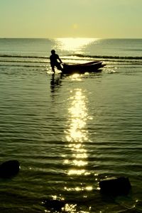 Silhouette of people in sea at sunset