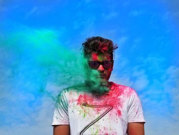 Man in multi colored smoke against blue sky