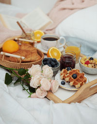 Romantic breakfast with coffee, waffles, orange juice and rose flowers.