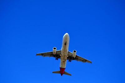 Low angle view of airplane against clear blue sky