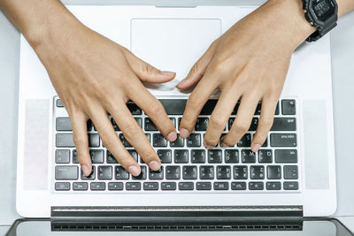 Cropped hands of man using laptop