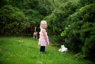 Full length portrait of happy girl standing on grassy field