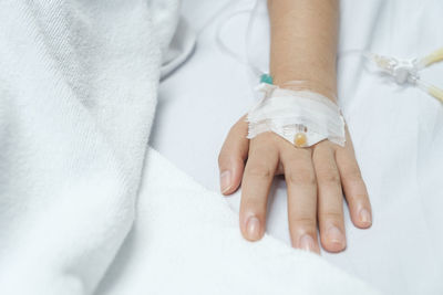 Close-up of hands and woman lying on bed