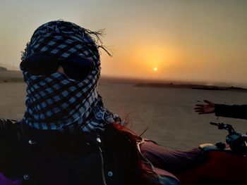 Portrait of woman wearing scarf on beach during sunrise