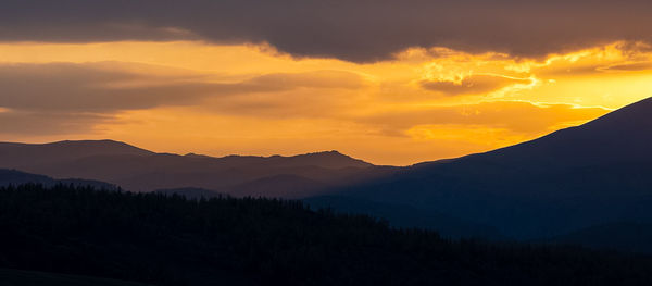 Scenic view of silhouette mountains against orange sky