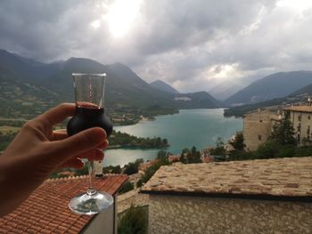 Person holding drink against mountain range