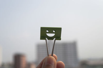 Close-up of hand holding clip against clear sky