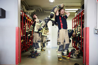 Firefighters wearing protective workwear in locker room while looking up at fire station