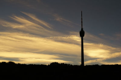 Silhouette of tower against cloudy sky during sunset