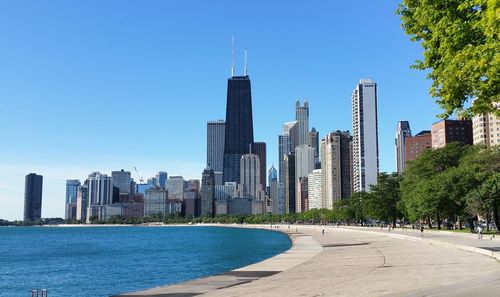 Chicago skyline from north avenue beach - buildings by lake michigan against clear blue sky