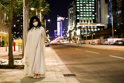 Portrait of woman standing on street in city at night