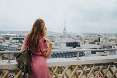 Rear view of woman looking at cityscape against sky