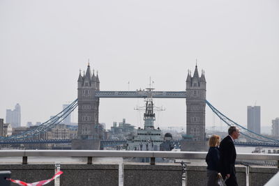 Rear view of people on suspension bridge against sky