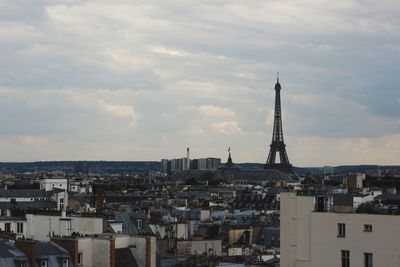 Aerial view of buildings in city against cloudy sky