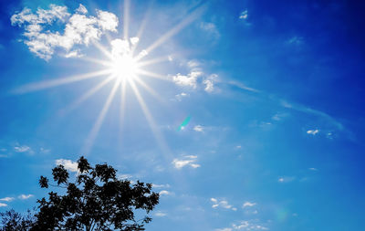 Low angle view of sunlight streaming through clouds