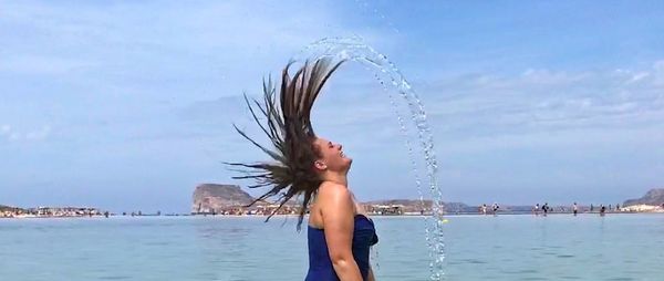 Woman standing in sea against sky