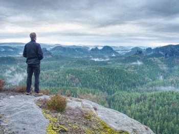 Man stop for watching misty landscape. moment on the edge of a cliff high above the misty forest