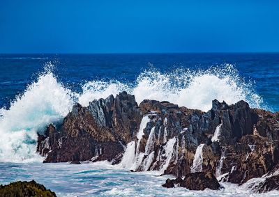 Panoramic view of rocks in sea against blue sky