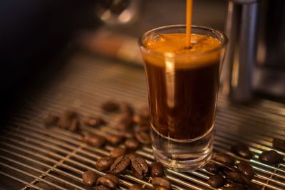 Close-up of coffee cup with roasted beans on metal grate