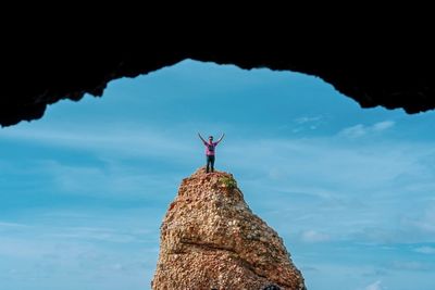 Man standing on rock against sky