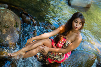High angle view of thoughtful young woman sitting in river