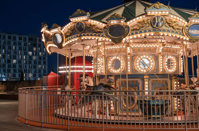 Illuminated carousel against sky at night